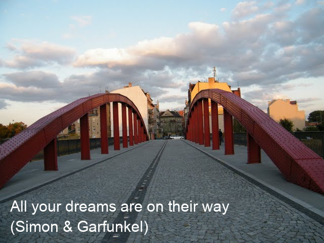 A photo of a red metal bridge at sunset with two lines of white caption near the bottom that read 'All your dreams are on their way' and 'Simon and Garfunkel'