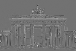 The Brandenburg Gate photograph after a 5 by 5 Gaussian-like blur. Edges of the architecture are softer; small details have dissolved into smooth tonal regions, but the overall composition is preserved.